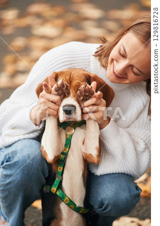 Covering the eyes with paws. Young woman is with her dog in the park Covering the eyes with paws. Young woman is with her dog in the park 129816728