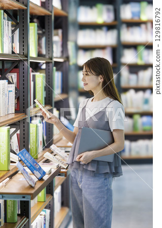 尋找一本書在圖書館裡的年輕女子 129816792