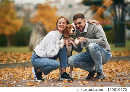 Sitting, resting. Lovely couple are with their cute dog outdoors Sitting, resting. Lovely couple are with their cute dog outdoors 129816870