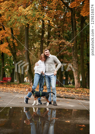 By the puddle. Lovely couple are with their cute dog outdoors 129816874