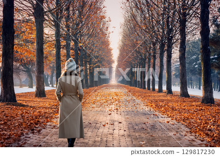 一位年輕女子沿著一排梧桐樹漫步 一位年輕女子沿著一排梧桐樹漫步 129817230