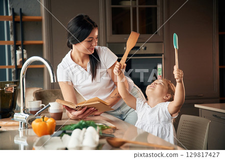 Mother with her daughter are preparing food on the kitchen 129817427