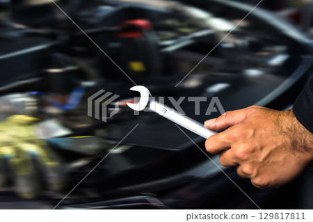 Car repair close up, mechanic hand holding open-end wrench in engine bay 129817811
