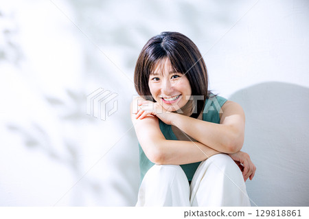 Summer sunlight: A woman leaning against a wall 129818861