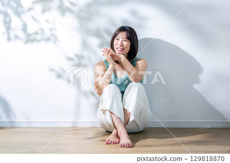 Summer sunlight: A woman leaning against a wall 129818870