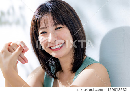Summer sunlight: A woman leaning against a wall 129818882