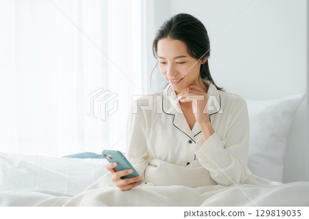 女人在床上操作智能手機 129819035