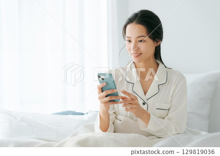 女人在床上操作智能手機 女人在床上操作智能手機 129819036