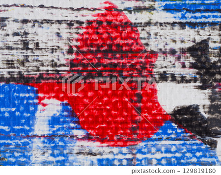 Abstract design featuring bold colors and textures on a weathered surface in an urban environment during daylight 129819180