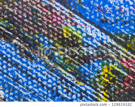 Vibrant abstract texture displays colorful patterns on a weathered surface in urban setting during daylight 129819182