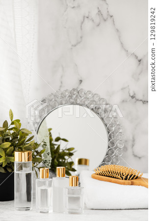 Morning skincare image of cosmetic bottles and accessories lined up on a windowsill 129819242