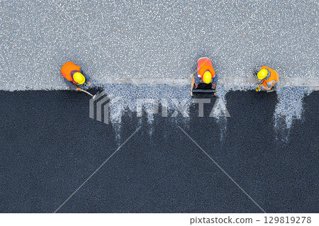 Close-up overhead shot of construction workers applying paint to a roof Close-up overhead shot of construction workers applying paint to a roof 129819278
