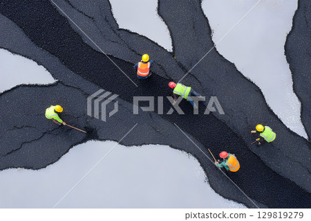 Close-up overhead shot of construction workers applying paint to a roof Close-up overhead shot of construction workers applying paint to a roof 129819279