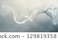 Wisps of delicate white smoke dance elegantly against a muted gray backdrop, forming abstract shapes that evoke a sense of calm and serenity in the viewer 129819358