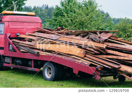 Truck carrying large load of wooden planks in a rural area during a cloudy day Truck carrying large load of wooden planks in a rural area during a cloudy day 129819708