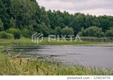 Serene lake surrounded by lush greenery under a cloudy sky in late afternoon Serene lake surrounded by lush greenery under a cloudy sky in late afternoon 129819770