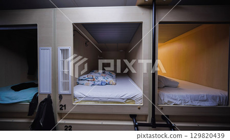 Row of capsule hotel rooms offering comfortable and private sleeping spaces 129820439