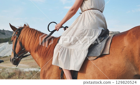 Woman riding brown horse in Crimea near Belogorsk Woman riding brown horse in Crimea near Belogorsk 129820524