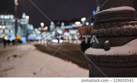 Snow covering ornate lamp post in Moscow at night with blurred background 129820541