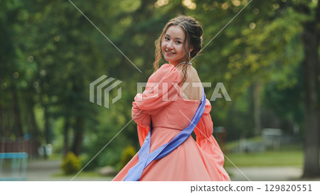 Graduate student wearing academic sash, beaming with pride, spinning joyfully amid green park landscape, symbolizing academic success Graduate student wearing academic sash, beaming with pride, spinning joyfully amid green park landscape, symbolizing academic success 129820551