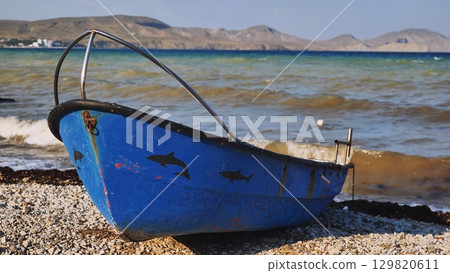 Vintage blue fishing boat adorned with marine wildlife art, sitting on rocky crimean coastline, black sea waters stretching behind wooden vessel Vintage blue fishing boat adorned with marine wildlife art, sitting on rocky crimean coastline, black sea waters stretching behind wooden vessel 129820611