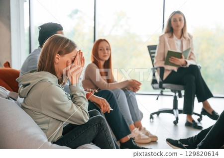 Psychologist is sitting and listening. Group of people are having therapy meeting together Psychologist is sitting and listening. Group of people are having therapy meeting together 129820614