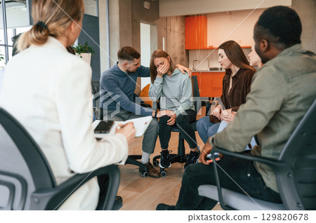 Woman is crying. Group of people are having therapy meeting together Woman is crying. Group of people are having therapy meeting together 129820678
