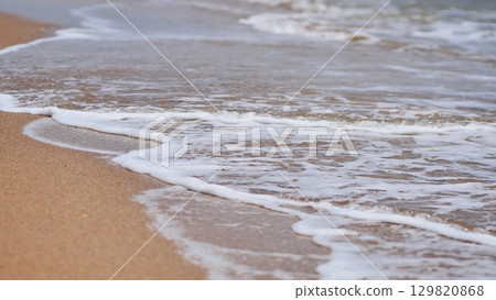 Gentle white sea foam caressing sandy shoreline in crimea, epitomizing tranquil coastal serenity 129820868