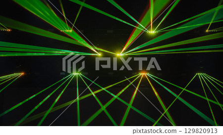 Green laser beams illuminating dark concert hall during music show 129820913