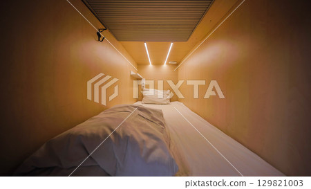 Capsule hotel room interior showing comfortable bed, pillow and led lights 129821003
