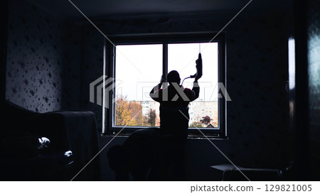 Silhouettes of builders drill the walls to install windows. 129821005