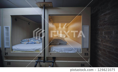Capsule hotel beds providing comfortable and private sleeping space 129821075