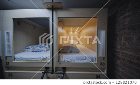 Capsule hotel beds providing comfortable and private sleeping space 129821076
