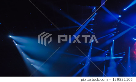 Blue stage lights illuminating dark concert hall during music festival Blue stage lights illuminating dark concert hall during music festival 129821105