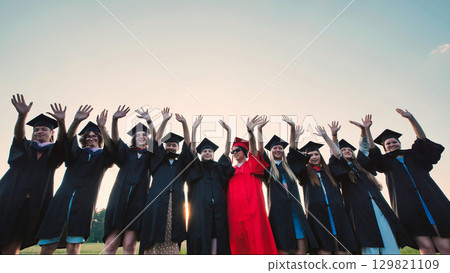 Happy graduates in caps and gowns celebrating their academic success outdoors Happy graduates in caps and gowns celebrating their academic success outdoors 129821109
