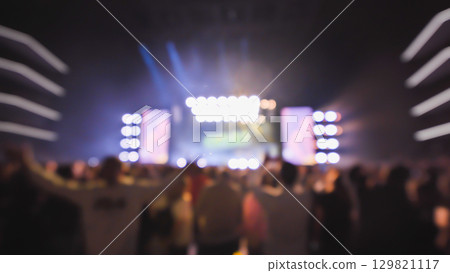 Crowd enjoying live music concert with bright lights shining on stage 129821117