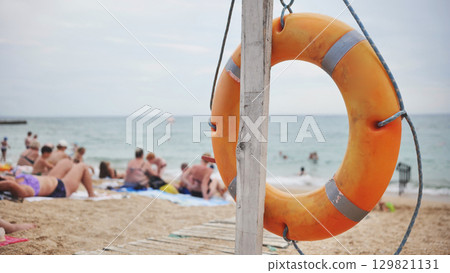 Orange lifebuoy hanging on wooden pole on Koktebel beach in Crimea Orange lifebuoy hanging on wooden pole on Koktebel beach in Crimea 129821131