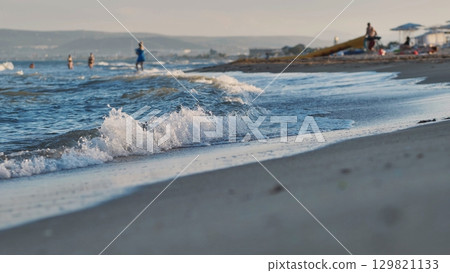 Gentle waves washing Crimean beach in summer evening Gentle waves washing Crimean beach in summer evening 129821133
