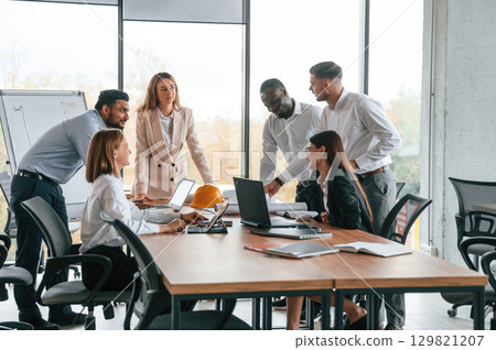 On the meeting, discussing the plans. Group of office workers are together indoors On the meeting, discussing the plans. Group of office workers are together indoors 129821207