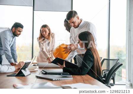 Against the panoramic window, having a meeting. Group of office workers are together indoors 129821213