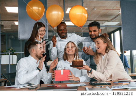 Cake with candles. Employee having a birthday in the office, group of workers Cake with candles. Employee having a birthday in the office, group of workers 129821238