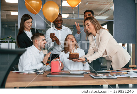 Cake with candles. Employee having a birthday in the office, group of workers Cake with candles. Employee having a birthday in the office, group of workers 129821240
