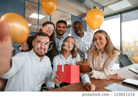 Selfie of happy woman with gift. Employee having a birthday in the office, group of workers Selfie of happy woman with gift. Employee having a birthday in the office, group of workers 129821258