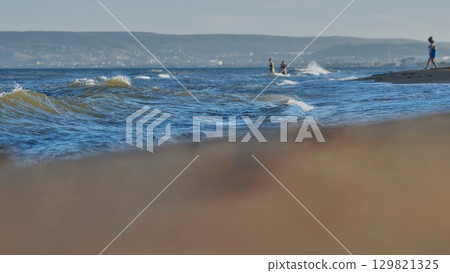 Gentle waves washing the sandy beach of the black sea in crimea, with tourists enjoying the summer day Gentle waves washing the sandy beach of the black sea in crimea, with tourists enjoying the summer day 129821325