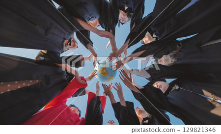 Graduates in academic gowns preparing to seize global opportunities after their graduation ceremony by touching a globe Graduates in academic gowns preparing to seize global opportunities after their graduation ceremony by touching a globe 129821346