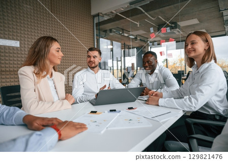 Sitting together by the table. Group of office workers are indoors 129821476