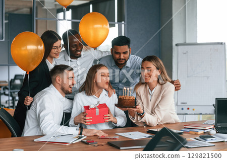 Celebration with cake, balloons and gift box. Employee having a birthday in the office, group of workers Celebration with cake, balloons and gift box. Employee having a birthday in the office, group of workers 129821500