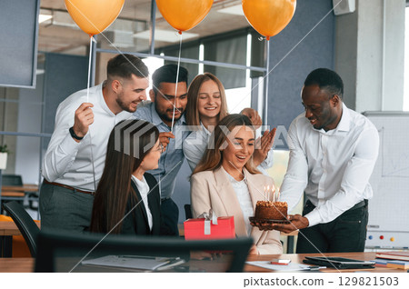 Celebration with cake, balloons and gift box. Employee having a birthday in the office, group of workers 129821503