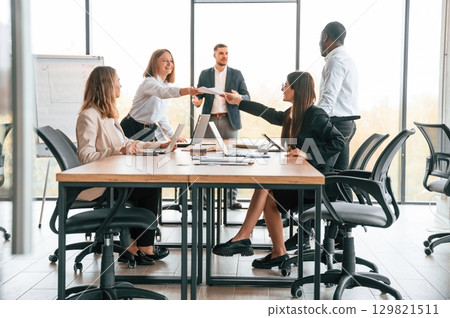 Giving the documents. Group of office workers are together indoors 129821511