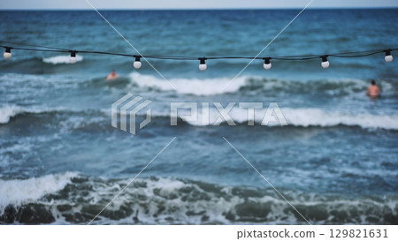 String of lights illuminating the beach in Crimea with tourists swimming in the sea 129821631